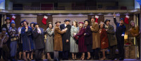 The song-and-dance duo Phil Davis (Evan C. Dolan, center, tan coat) and Bob Wallace (Alex Syiek, from left, black coat) meet cute on a crowded train ride to Vermont with sisters Betty Haynes (Sophie Grimm, light blue coat) and Judy Haynes (Jessie J. Potter, in purple) in Irving Berlin’s White Christmas.